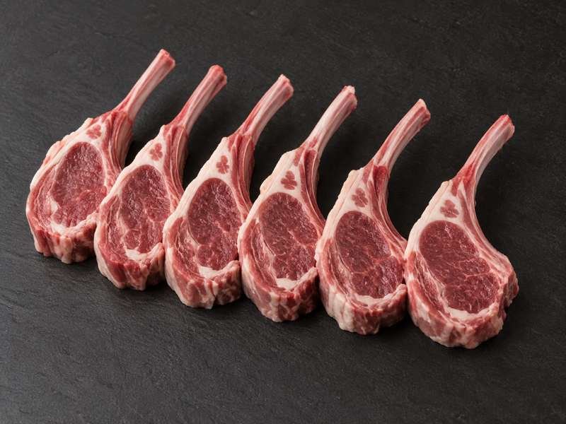 Six raw lamb rib chops laid side by side