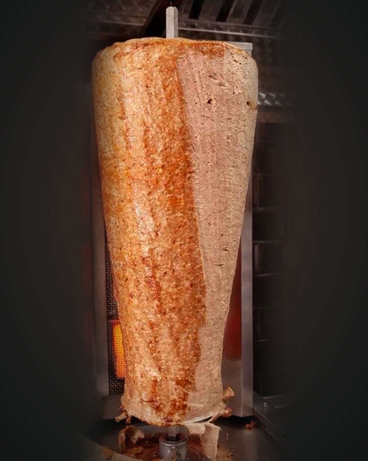 Whole lamb doner of finely minced lamb on a vertical grill, browned down one side